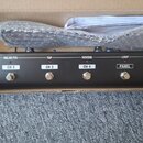 Černý efektový pedál v kartonové krabici. Na horní straně jsou nápisy BOOSTER/MOD, DELAY/FX, TAP, REVERB a LOOP s červenými kontrolkami, dále označen…