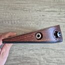 Detailní pohled na hranu hnědého dřevěného nástroje. Jsou vidět dva kovové konektory, z nichž jeden je označen nápisem IN. Spodní hrana nástroje má v…