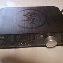 Černý audio rozhraní s kovovým povrchem a logem stylizované postavy v kruhu na horní straně. Na předním panelu jsou nápisy ONYX Artist 1-2, LINE/INST…
