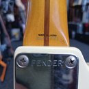 Detail zadní strany hрифu a hlavy elektrické kytary. Na dřevěném hrifu je černý nápis MADE IN JAPAN a pod ním vyrazené sériové číslo F017527. Kový kr…