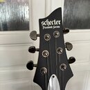 Fotografie zachycuje hlavu černé elektrické kytary. Na čele je bílý nápis schecter a pod ním menší text Diamond Series. Jsou vidět šest ladicích kol…