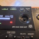 Detailní pohled na ovládací panel černého digitálního přehrávače. Na displeji je vidět čas 22:22.98, hodnota 0.00% a 120 BPM, dále seznam stop PACK01…