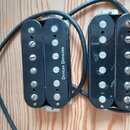 Dvě černé humbucker snímače s kovovými kryty a viditelnými polosnovými magnety. Na obou snímačech je svisle vyražen bílý nápis DUNCAN DESIGNED. Povrc…