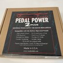 Kartonová krabice s produktem Voodoo Lab PEDAL POWER 2 PLUS. Na povrchu je nápis UNIVERSAL POWER SUPPLY FOR GUITAR PEDAL EFFECTS a seznam technických…
