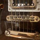 Detailní záběr na spodní část trupu černé elektrické kytary. Je vidět chromovaný humbucker s šesti polkovými šrouby, Tune-o-matic kobylka a stopbar s…