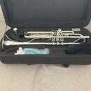 Stříbrný mosazný nástroj typu flugelhorn v černém kufru. Na nástroji nejsou viditelná žádná loga ani nápisy. Součástí je potrubí, tři ventily a modrý…