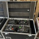 Otevřený černý transportní case s hliníkovým profilem a kovovými zámky, v němž jsou umístěny čtyři černé elektronické jednotky. Zařízení mají na horn…