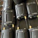 Fotografie zobrazuje několik černých DI boxů s kovovým šasi a mřížkou. Na zařízeních jsou bílé samolepky s nápisy „eGtr Pata“, „Mandoline“, „eGtr MZ“…