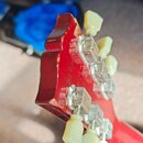 Detail hlavy červené elektrické kytary z pohledu zadu. Jsou vidět kovové ladičky s bílými plastovými knoflíky. Povrch laku v horní části hlavy vykazu…