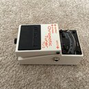 Bílý ladicí pedál s černým spínacím tlačítkem. Na zařízení jsou nápisy BOSS, Chromatic Tuner TU-3, OUTPUT, BYPASS, INPUT, PITCH, MODE a CHECK. V prav…