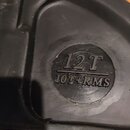 Detail černého plastového kufru s nápisy. V kruhovém vyrytém poli je text 12T a pod ním v obdélníku 10T+RMS. Ve spodní části je vidět žlutá nálepka s…