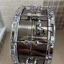Černý snare drum s chromovaným obručováním a hardwarem. Na korpusu jsou vidět nápisy "LUDWIG" na horních a dolních lugách. Nástroj vykazuje známky po…