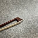 Detailní pohled na hmatník a horní hranu krku smyčcového nástroje. Nástroj je vyroben z tmavě hnědého dřeva s bílým lemováním na hraně. Povrch je hla…