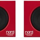 Dva červené studiové monitory s černými mřížkami reproduktorů. Na pravém dolním rohu levého a v levém dolním rohu pravého reproduktoru je bílý nápis…