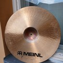 Zlatavý mosazný činel s viditelným rýhováním a kovaným povrchem. V dolní části je černý nápis MEINL s logem a pod ním menší text ROLAND MEINL. Povrch…