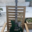 Tmavě zelená elektrická kytara s hmatníkem z tmavého dřeva a bílými vložkami. Na hlavě je viditelné logo značky Yamaha. Kytara má dva humbuckery, jed…