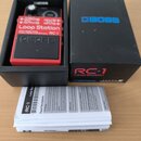 Červený efekt pedál Boss RC-1 Loop Station v originální černé krabici spolu s přiloženým manuálem. Na pedálu jsou nápisy OUTPUT A, OUTPUT B, INPUT A,…
