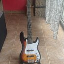 Elektrická basová kytara s korpusem v přechodovém lakování od černé přes červenou po žlutou. Nástroj má bílý pickguard a na hlavě hmatníku je nápis "…
