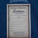 Fotografie zobrazuje papírový Certifikát pravosti (Certificate of Authenticity) značky Eastman. Dokument obsahuje nápis HANDCRAFTED GUITARS & MANDOLI…