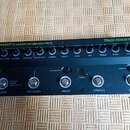 Černý předzesilovač s efekty Trace Acoustic Transit-A Acoustic Pre-Amp and Effects. Horní řada obsahuje deset otočných potenciometrů s popisky Output…