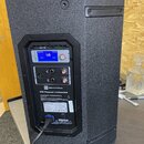 Černý aktivní reproduktor s texturovaným povrchem. Na zadním panelu je nápis Electro-Voice a model ETX Powered Loudspeaker, dále modrý displej s hodn…