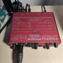 Červené audio rozhraní s nápisy EDIROL, Audio Capture FA-66 a FireWire. Na přední straně jsou potenciometry, přepínače a konektory, z nichž jeden je…