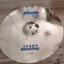 Kovový činel v zlatavé barvě s kovaným, důlkovaným povrchem. Na horní části je modrý nápis PAiSte a pod ním červený nápis 2000. Ve spodní části je mo…