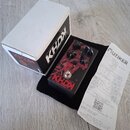 Černý kytarový efekt s červeným grafickým motivem a nápisy KHDX a DARK BLOOD. Na horní straně jsou tři černé ovládací knoflíky s popisky GAIN, TONE a…