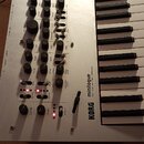 Stříbrný polyfonní analogový syntetizér s klávesnicí. Na panelu jsou nápisy minilogue, POLYPHONIC ANALOGUE SYNTHESIZER a KORG. Nástroj obsahuje množs…