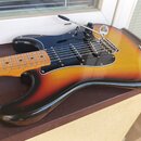 Elektrická kytara s korpusem v barevném přechodu od žluté přes oranžovou k červené a černé. Nástroj má černý pickguard, tři snímače a javorový hmatní…