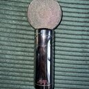 Stříbrný kondenzátorový mikrofon s kovovou síťkou v horní části a lesklým chromovaným tělem. Na těle je svisle vyražen nápis M-AUDIO a v dolní části…