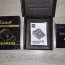 Na fotografii je kytarový efekt Shred Master od značky Marshall, jeho originální krabice a manuál. Pedál je černý s ovládacími knoflíky, červenou LED…