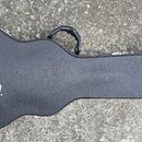 Černý tvrdý kufýr na kytaru s texturovaným povrchem. Na spodní části je bílý nápis Gibson USA. Kufýr má v horní části plastovou úchytnou rukojeť.