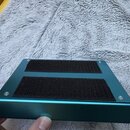 Modrý kovový efekt pedál s dvěma černými texturovanými plochami pro došlap. Zařízení je drženo štyřmi viditelnými šrouby v rozích. Povrch kovového ša…