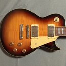 Elektrická kytara s tvarem Les Paul v barevném provedení sunburst. Nástroj má dva humbuckery, čtyři ovládací knoflíky a bílý pickguard. Na horním roh…