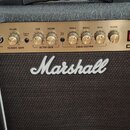 Kytarový kombozesilovač značky Marshall, model DSL1. Zlatý ovládací panel obsahuje nápisy VOLUME (dvakrát), GAIN, TREBLE, MIDDLE, BASS a REVERB, přep…