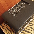 Černý kytarový kombo zesilovač s povrchem z texturovaného vinylu. Na horním ovládacím panelu jsou umístěny voličky a potenciometry s nápisy Gain, Bas…