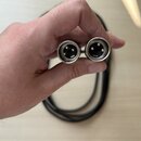 Ruka drží dva konce černého kabelu s kovovými konektory typu XLR. Jsou vidět tři vnitřní piny v každém konektoru. Povrch kovových částí je stříbrný a…