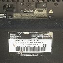 Detail zadní strany černého elektronického zařízení s napájecím vstupem a vypínačem. Na horním štítku jsou nápisy Fuse Rating F3.15AL/230V, CAUTION R…