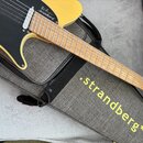 Žlutá elektrická kytara s černým pickguardem položená na šedém pouzdře. Na těle kytary je bílý nápis „Silen .strandberg*“ a na pouzdře žlutý nápis „.…