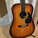 Akustická kytara s tělem tvaru dreadnought v barevném provedení sunburst (přechod od žluté k tmavě hnědé). Nástroj má černý trsací plech, tmavý hmatn…