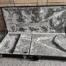 Otevřený černý tvrdý kufýr s vnitřním polstrováním z šedého plyšového materiálu. V dolní části jsou vyryté přihrádky pro nástroj a příslušenství. Pov…