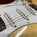 Elektrická kytara s krémovým povrchem těla a bílým pickguardem. Nástroj má tři bílé snímače typu single-coil a chromovaný kobylník. Na hmatníku jsou…