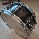 Černý buben s chromovaným kováním a bílýmI skiny. Na horním obruči je nápis SONOR 2.3mm Bass Hoop, na skinu je viditelné logo REMO. Povrch korpusu vy…