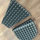 Dvě šedé akustické panely s pyramidovou strukturou povrchu, umístěné na dřevěné podlaze. Panely mají černý lem a jsou zakončeny zipy po okrajích. Pov…