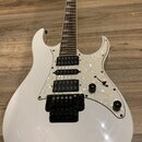 Bílá elektrická kytara s perleťovým pickguardem a černým hardwarem. Na hmatníku jsou vidět čtyři snímače typu humbucker a jeden ovládací knoflík s př…