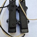 Dva černé elektrické snímače pro kytaru s plastovými kryty a připojenými vodiči. Snímače jsou v základním černém provedení bez viditelných značek, lo…