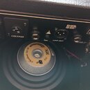 Detail zadní strany černého kytarového komba. V horní části je vidět logo DV MARK, přepínač s nápisem VOLTAGE a hodnotou 240, konektor LINE OUT s pop…