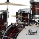 Detailní pohled na bicí sadu v tmavě červeném provedení s pruhy. Na bílém předním obalu basového bubnu je černý nápis Pearl. Sestava obsahuje několik…