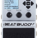 Stříbrný efekt pedál s displejem, na kterém je text: „Blues 1 Genre: Blues Time sig. 4/4 Stopped Drum set:Standard Vol 84% 100 BPM“. Nad ním jsou čty…